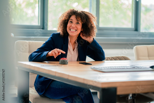 Cheerful businesswoman with buzzer button in board room photo