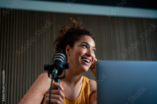 Happy radio presenter with microphone podcasting at workplace photo