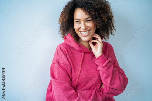 Happy woman wearing hooded shirt in front of white wall