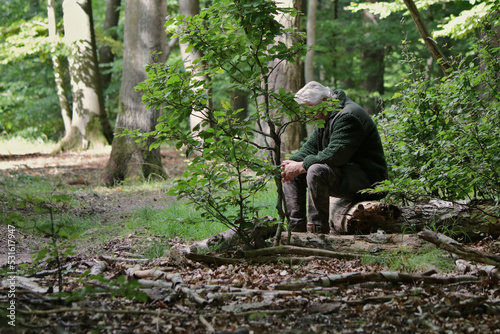 Mann mit grauen Haaren sitzt einsam und verzweifelt im Wald