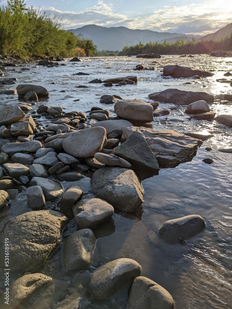 Beautiful cloudy sky at sunset over the river. The high bank of the river is overgrown with grass. Beautiful cloudy sky at sunset over the river. The high bank of the river is overgrown with grass.