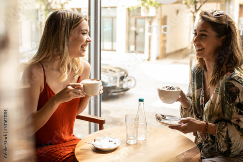 two women drinking coffee in cafe
Smiling and having a cheerfull talk photo