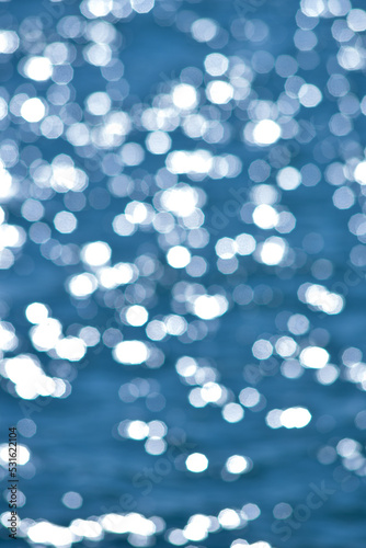 Out of focus shining light as the sun hits the ocean. The abstract bokeh effect creating sparkles.