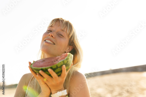 Cheerful young woman enjoy at tropical sand beach. Portrait of happy girl with fruit. Young woman having a picnic on the beach.. photo