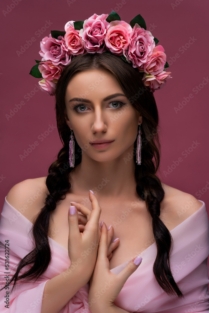 Naklejka premium A wreath of pink roses is a beautiful headdress for a girl. Portrait of an attractive young Ukrainian woman in a wreath with clean skin. Concept wedding style or beauty salon and skin care.