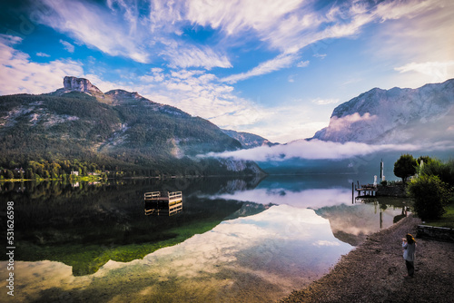 Breathtaking morning view of a woman standing on the shore of Altausseer See (Lake Aussee), Styria, Austria, drinking coffee and looking at the lake photo