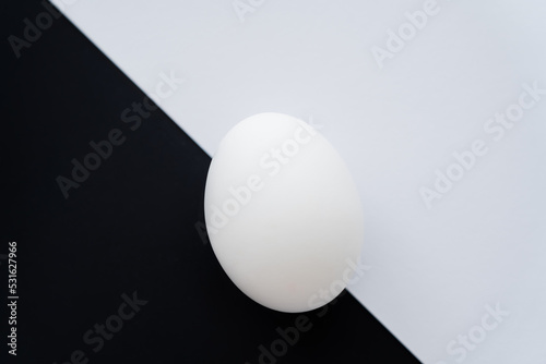 Top view of organic chicken egg on white and black background.