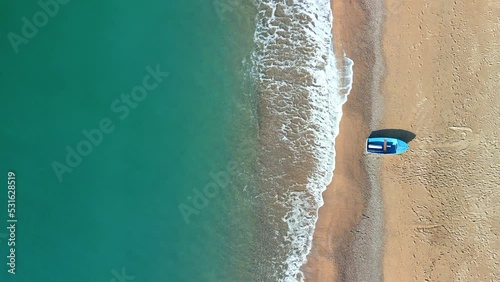 Overhead aerial image of a beach with a small fishing boat static shot photo