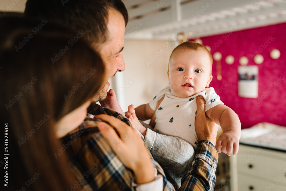Happy family, parenthood and people concept - mother, father with baby at home. Portrait of young smiling family with son on the hands. Happy family, parenthood and people concept - mother, father with baby at home. Portrait of young smiling family with son on the hands.