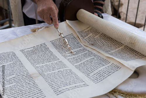 Closeup of a hand holding a yad or pointer to guide the reader through the Hebrew text of the Jewish Torah. photo