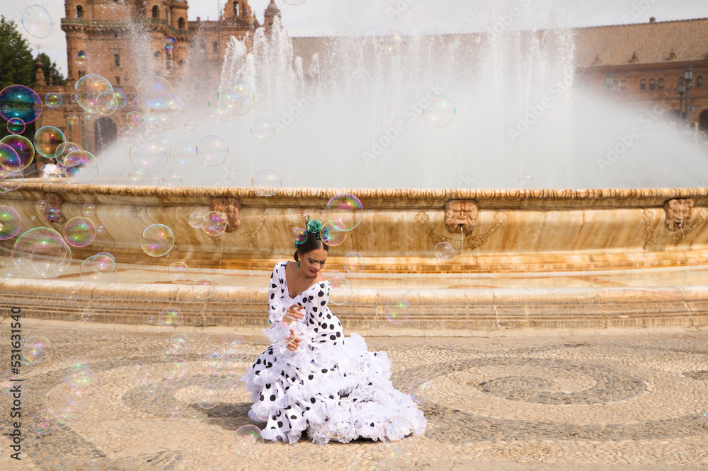 Flamenco dancer woman, teenage brunette and beautiful typical Spanish dancer is dancing between soap bubbles in front of a fountain. Flamenco concept of the cultural heritage of humanity - obrazy, fototapety, plakaty 
