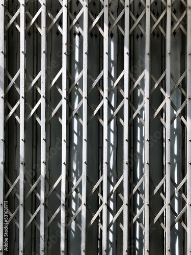 Traditional 2 layers scissor and folding panel thai chinese cast metal door style in gray color under afternoon sunlight