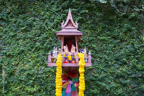 Traditional thai wooden holy house with yellow flower garland and colorful fabric