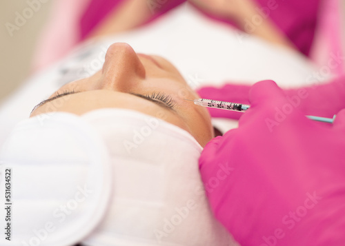 Tableau sur toile Close-up of young woman getting rejuvenation beauty injection into skin under eyes for modification of facial contour