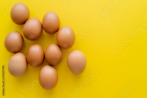 Top view of brown eggs on yellow background.