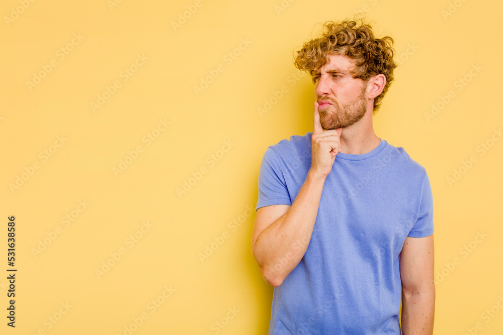 Young caucasian man isolated on yellow background looking sideways with doubtful and skeptical expression. Young caucasian man isolated on yellow background looking sideways with doubtful and skeptical expression.