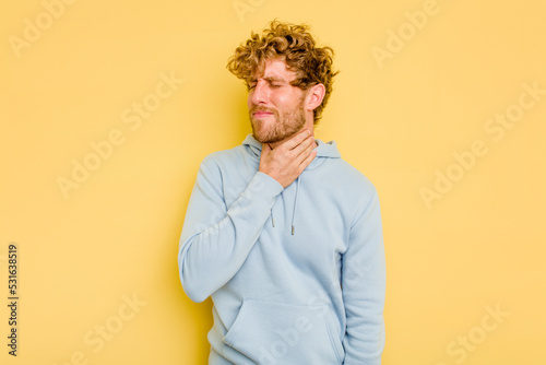 Young caucasian man isolated on yellow background suffers pain in throat due a virus or infection.