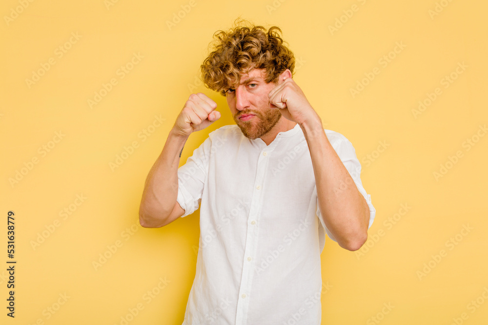 Young caucasian man isolated on yellow background throwing a punch, anger, fighting due to an argument, boxing. Young caucasian man isolated on yellow background throwing a punch, anger, fighting due to an argument, boxing.