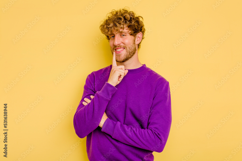 Young caucasian man isolated on yellow background smiling happy and confident, touching chin with hand. Young caucasian man isolated on yellow background smiling happy and confident, touching chin with hand.