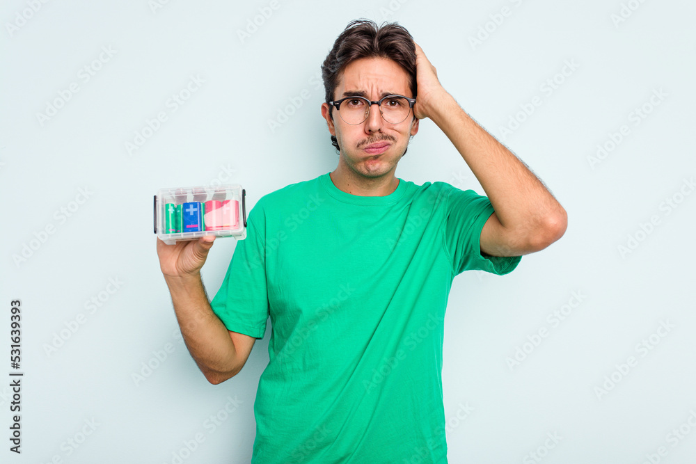 Young hispanic man holding battery box isolated on white background being shocked, she has remembered important meeting. Young hispanic man holding battery box isolated on white background being shocked, she has remembered important meeting.