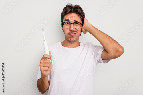 Young hispanic man holding electric toothbrush isolated on white background being shocked, she has remembered important meeting.