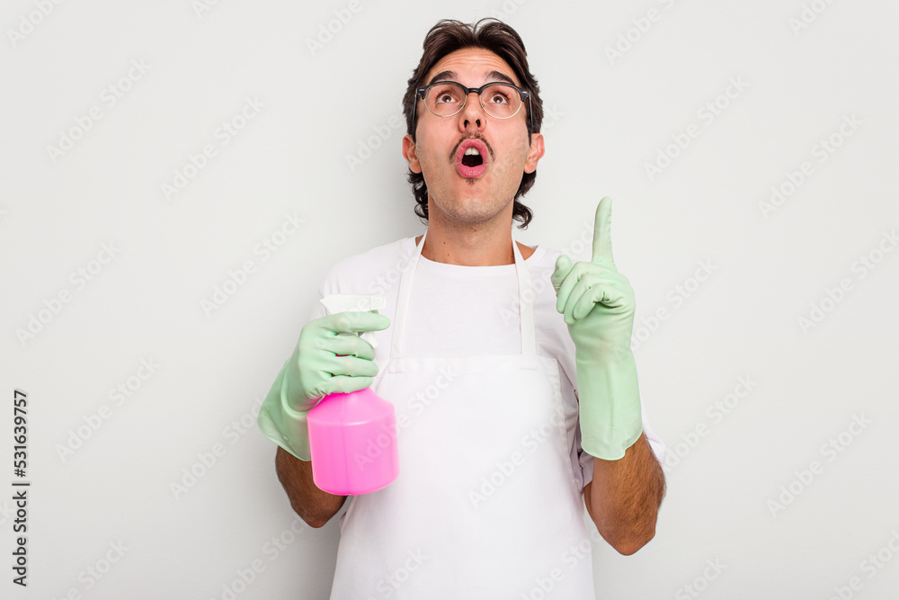 Young cleaner hispanic man isolated on white background pointing upside with opened mouth. Young cleaner hispanic man isolated on white background pointing upside with opened mouth.