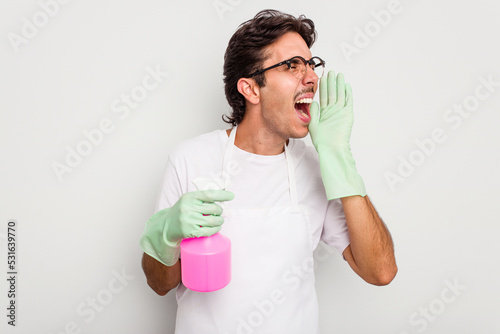 Young cleaner hispanic man isolated on white background shouting and holding palm near opened mouth.