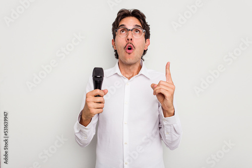 Young hispanic singer man isolated on white background pointing upside with opened mouth.