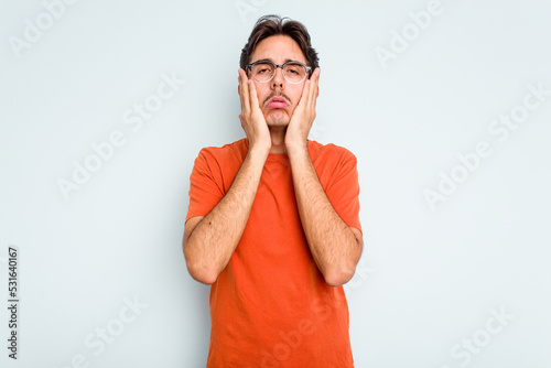 Young hispanic man isolated on blue background whining and crying disconsolately.