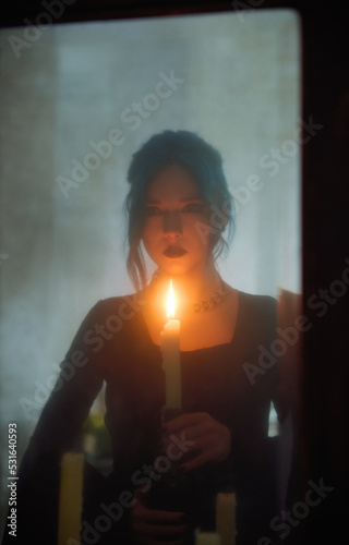 Indoors portrait of sad goth girl with candle. Blue-haired gothic lady looking into old dirty mirror. Young witch. Vintage style