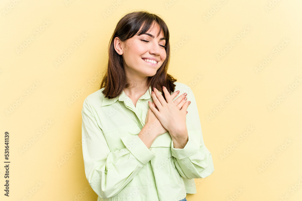 Young caucasian woman isolated on yellow background has friendly expression, pressing palm to chest. Love concept. Young caucasian woman isolated on yellow background has friendly expression, pressing palm to chest. Love concept.