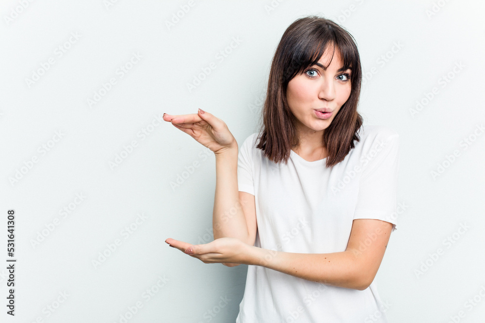 Young caucasian woman isolated on white background shocked and amazed holding a copy space between hands. Young caucasian woman isolated on white background shocked and amazed holding a copy space between hands.