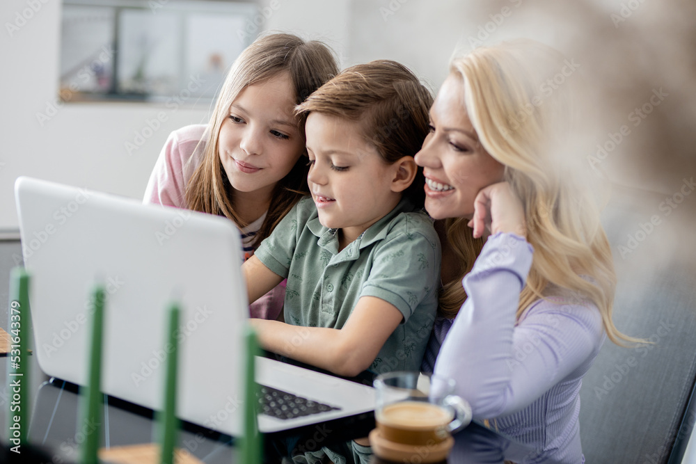 Single mother with two kids watching something on laptop Single mother with two kids watching something on laptop