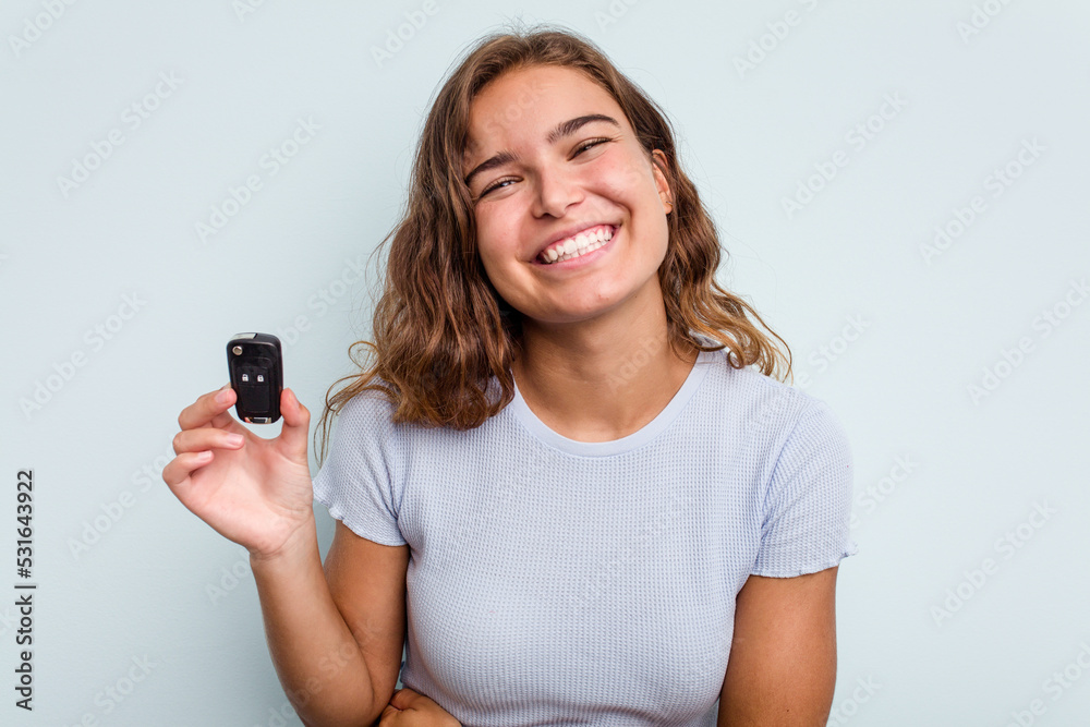 Young caucasian woman holding car keys isolated on blue background laughing and having fun. Young caucasian woman holding car keys isolated on blue background laughing and having fun.