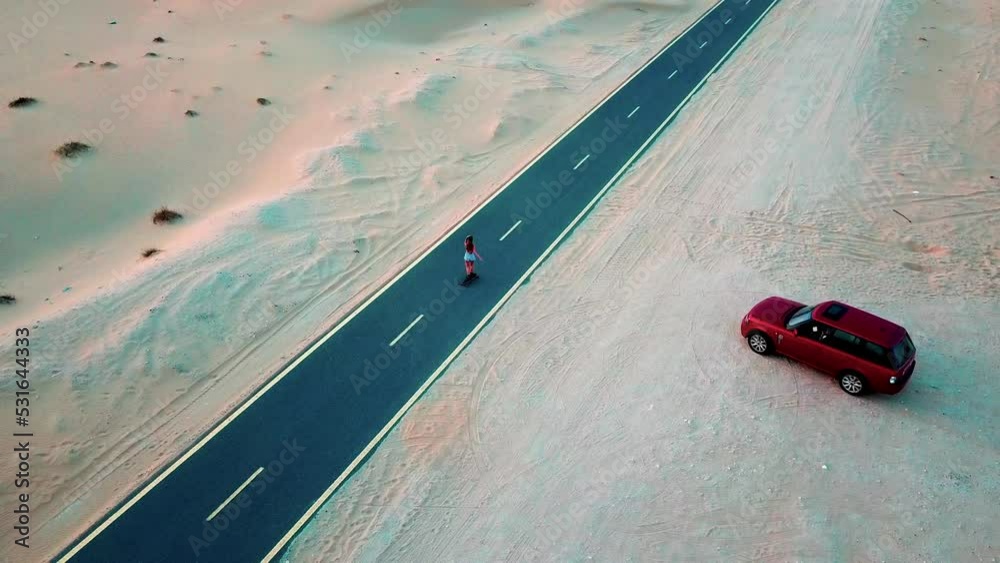 Girl rides on a skateboard on a desert road