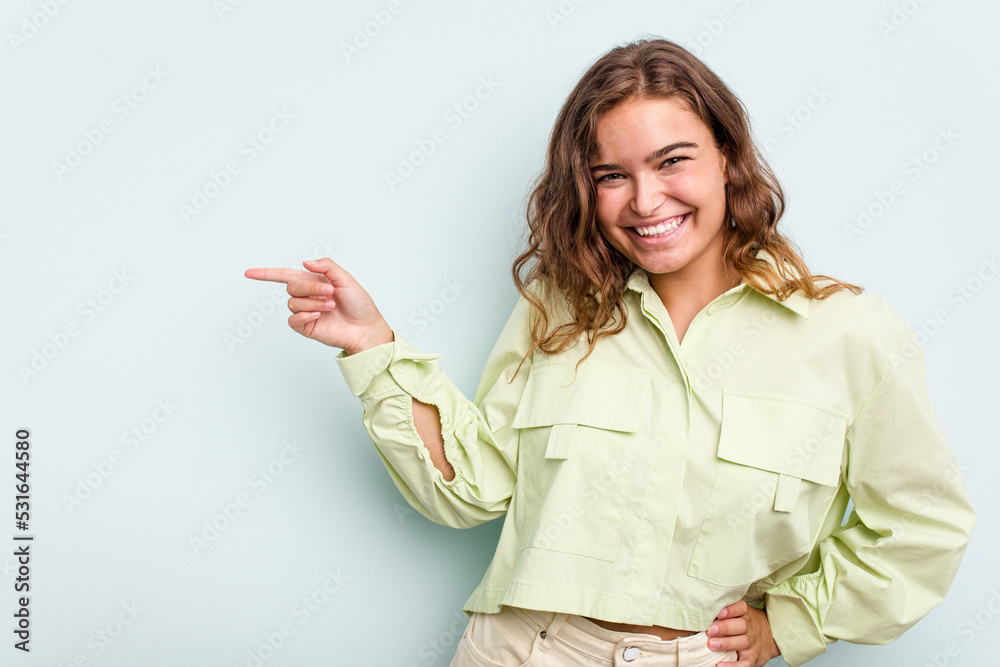 Young caucasian woman isolated on blue background smiling cheerfully pointing with forefinger away. Young caucasian woman isolated on blue background smiling cheerfully pointing with forefinger away.