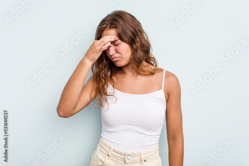 Young caucasian woman isolated on blue background having a head ache  touching front of the face.