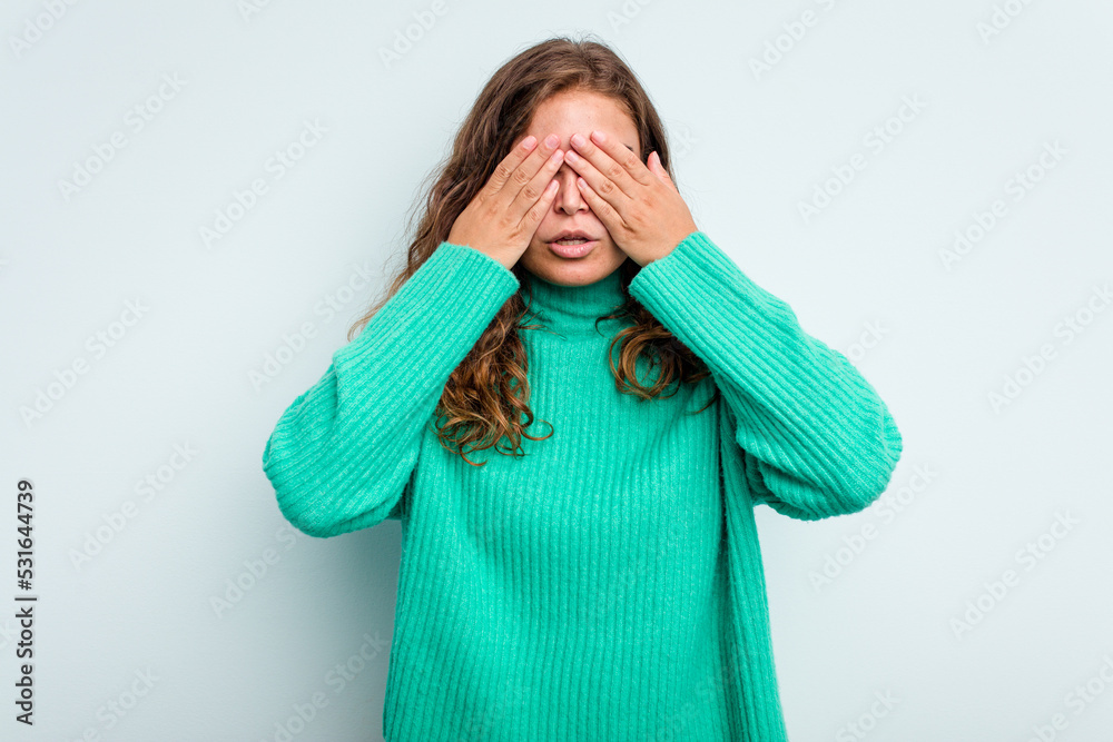 Young caucasian woman isolated on blue background afraid covering eyes with hands.