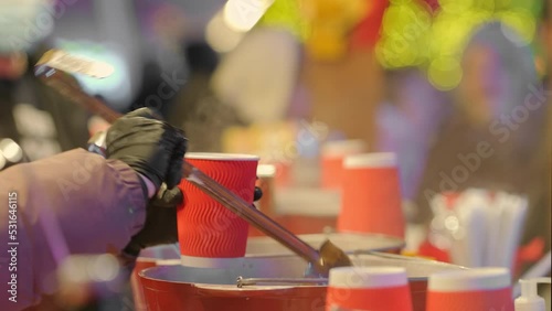 Street vendor pouring mulled wine in cups at traditional Christmas market photo