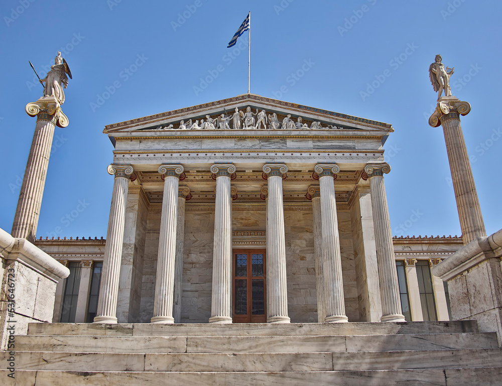 The national university of Athens neoclassical front, Greece. Athena and Apollo ancient gods marble statues are standing on corinthian rythm columns, under the clear blue sky.