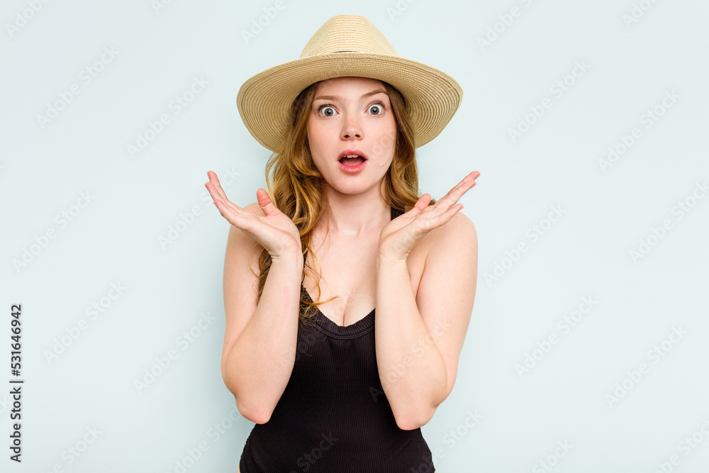 Young caucasian woman going to the beach isolated on blue background surprised and shocked. Young caucasian woman going to the beach isolated on blue background surprised and shocked.