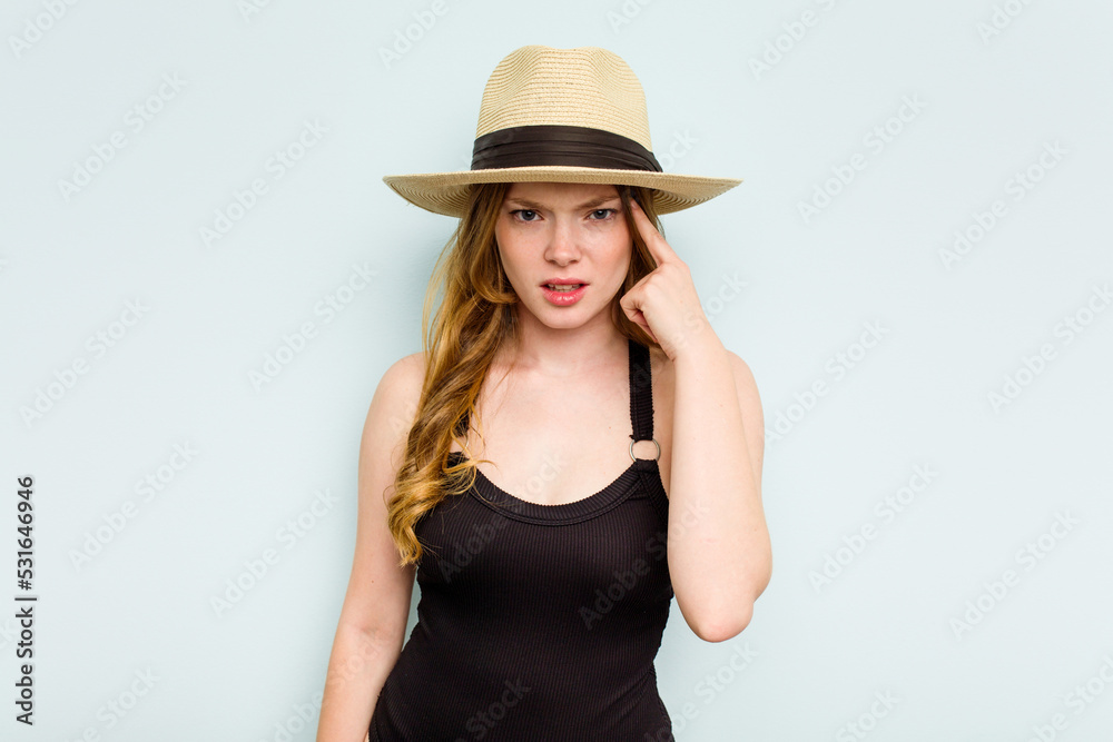 Young caucasian woman going to the beach isolated on blue background showing a disappointment gesture with forefinger. Young caucasian woman going to the beach isolated on blue background showing a disappointment gesture with forefinger.