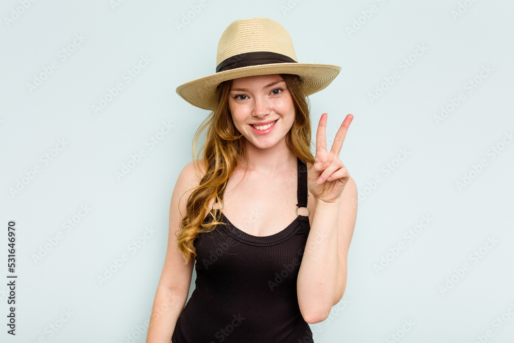 Young caucasian woman going to the beach isolated on blue background showing number two with fingers. Young caucasian woman going to the beach isolated on blue background showing number two with fingers.