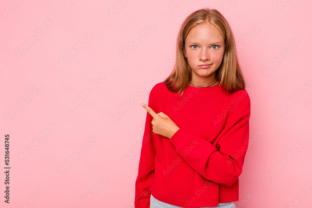 Caucasian teen girl isolated on pink background smiling and pointing aside, showing something at blank space. Caucasian teen girl isolated on pink background smiling and pointing aside, showing something at blank space.