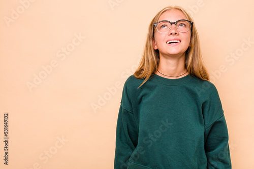 Caucasian teen girl isolated on beige background shouting very angry, rage concept, frustrated.