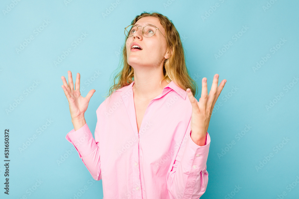 Fototapeta premium Young caucasian woman isolated on blue background screaming to the sky, looking up, frustrated.