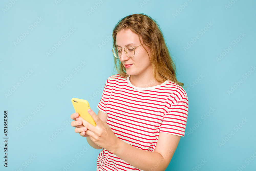 Young caucasian woman holding mobile phone isolated on blue background Young caucasian woman holding mobile phone isolated on blue background
