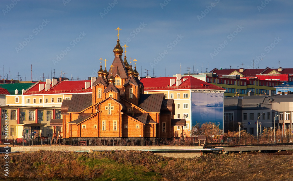Large wooden cathedral in the northern town. View of the church and colorful buildings. Cathedral of the Holy Trinity, City of Anadyr, Chukotka Autonomous Okrug, Siberia, Far East of Russia.