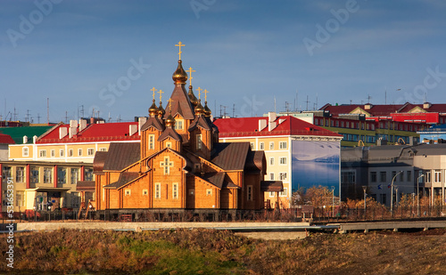 Large wooden cathedral in the northern town. View of the church and colorful buildings. Cathedral of the Holy Trinity, City of Anadyr, Chukotka Autonomous Okrug, Siberia, Far East of Russia.
