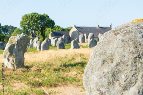 Closeup of a stone megalith in the archeological site of Carnac, Brittany, France. Coutriside with menhir in the blurred background. Selective focus. photo